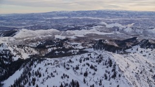 AX124_084E - 5.5K aerial stock footage of flying over snowy mountain ridge in winter at sunrise in Wasatch Range, Utah