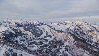 AX124_093E - 5.5K aerial stock footage of upscale Park City homes by snowy mountain slopes in Park City at sunrise, Utah