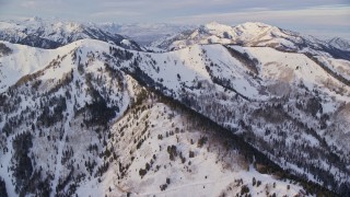 AX124_096E - 5.5K aerial stock footage tilt from mansions and roads to approach snowy ridge in winter at sunrise, Wasatch Range, Utah