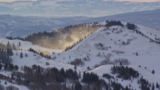 AX124_102 - 5.5K aerial stock footage of snowdrifts blowing off a mountain at sunrise in the Wasatch Range, Utah