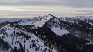 AX124_117E - 5.5K aerial stock footage approach two Wasatch Range peaks with snow at sunrise in Utah's Wasatch Range