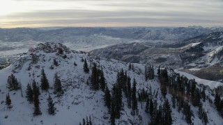 AX124_123 - 5.5K aerial stock footage fly over Clayton Peak with winter snow and reveal valley at sunrise in the Wasatch Range, Utah