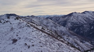 AX124_176E - 5.5K aerial stock footage the summit of Grandeur Peak with winter snow at sunrise in Utah