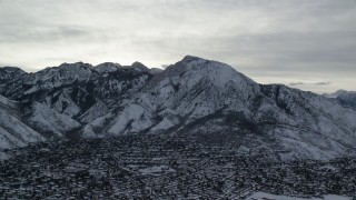 AX124_183 - 5.5K aerial stock footage of winter snow on Mount Olympus and Salt Lake City suburbs at sunrise in Utah