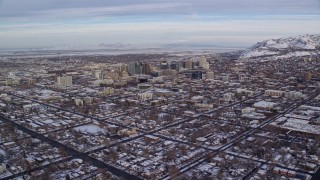 AX124_192E - 5.5K aerial stock footage approach Downtown Salt Lake City from suburbs with snow at sunrise, Utah