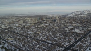 AX124_193 - 5.5K stock footage aerial video approach Downtown Salt Lake City with winter snow at sunrise in Utah