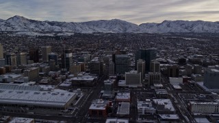 AX124_207E - 5.5K aerial stock footage passing Downtown Salt Lake City and Salt Palace with winter snow at sunrise in Utah