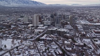 AX124_220E - 5.5K aerial stock footage orbit snowy Utah State Capitol to approach Downtown Salt Lake City in winter at sunrise