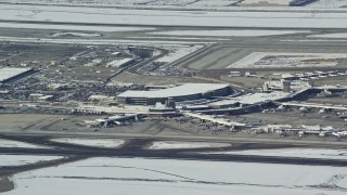AX125_009 - 5.5K aerial stock footage of Salt Lake City International Airport terminals with winter snowing Utah