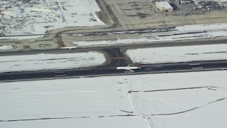AX125_011E - 5.5K aerial stock footage track airliner landing at Salt Lake City International Airport with winter snow in Utah