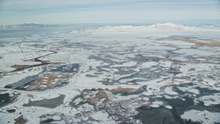 AX125_018 - 5.5K aerial stock footage fly over frozen marshlands to approach snowy Antelope Island in winter, Utah