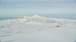 AX125_029 - 5.5K aerial stock footage pan across snow mountains on Antelope Island in wintery Utah