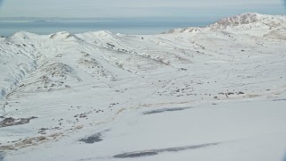 AX125_030E - 5.5K aerial stock footage of panning across wintery mountains on Antelope Island with snow in Utah