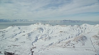 AX125_033E - 5.5K aerial stock footage of snowy Antelope Island mountains in wintertime Utah