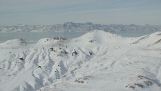 AX125_035 - 5.5K aerial stock footage of snowy mountain summits on Antelope Island in winter, Utah