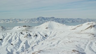 AX125_035E - 5.5K aerial stock footage of snowy mountain summits on Antelope Island in winter, Utah