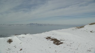 AX125_039 - 5.5K aerial stock footage flyby snowy mountain ridge to reveal Great Salt Lake in Utah
