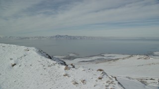 AX125_042 - 5.5K aerial stock footage of snowy shore of Antelope Island and Great Salt Lake in wintertime, Utah