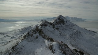 AX125_048 - 5.5K stock footage aerial video fly over snowy mountain ridge on Antelope Island in winter, Utah