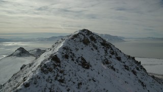 AX125_051 - 5.5K aerial stock footage fly over snowy Antelope Island peak toward Great Salt Lake in winter, Utah