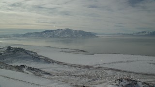 AX125_052 - 5.5K aerial stock footage approach frozen shore of Antelope Island and Great Salt Lake in winter, Utah