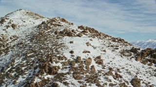 AX125_063 - 5.5K aerial stock footage orbiting rocky slopes of a peak in winter with snow on Utah's Antelope Island