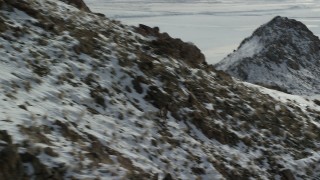 AX125_068 - 5.5K aerial stock footage track a bighorn sheep racing across rocks and snow in wintertime, Antelope Island, Utah
