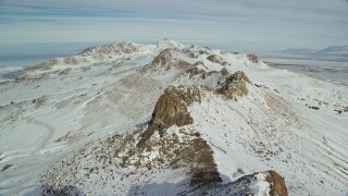 AX125_076E - 5.5K aerial stock footage of flying over a jagged mountain ridge with winter snow on Antelope Island, Utah