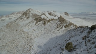 AX125_078 - 5.5K aerial stock footage fly over a rocky mountain ridge with winter snow, Antelope Island, Utah