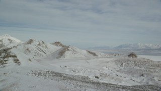 AX125_088 - 5.5K aerial stock footage approach and pan to snow mountains on Antelope Island in winter, Utah