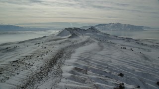 AX125_091 - 5.5K aerial stock footage of flying over light snow on the ground toward snow mountains, Antelope Island, Utah