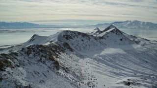 AX125_093E - 5.5K aerial stock footage approach and fly over a snowy mountain ridge on Antelope Island, Utah