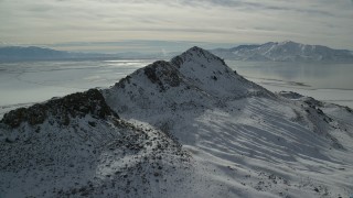 AX125_096 - 5.5K aerial stock footage of approaching a mountain reak with winter snow on Antelope Island, Utah