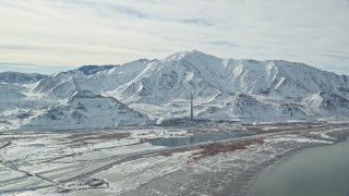 AX125_106 - 5.5K aerial stock footage approach Kennecott Smokestack and Oquirrh Mountains in winter, Utah
