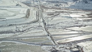 AX125_107 - 5.5K aerial stock footage orbit Interstate 80 through frozen countryside near Magna, Utah