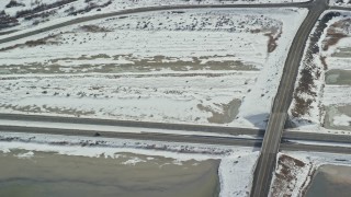AX125_108 - 5.5K aerial stock footage of tracking an SUV on Interstate 80 through winter countryside in Magna, Utah