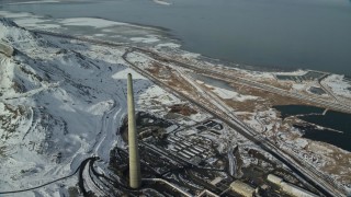 AX125_114E - 5.5K aerial stock footage of top of Kennecott Smokestack near the snowy shore of Great Salt Lake in Magna, Utah