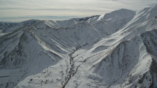 AX125_116 - 5.5K aerial stock footage of snowy mountain ridge in winter in the Oquirrh Mountains, Utah