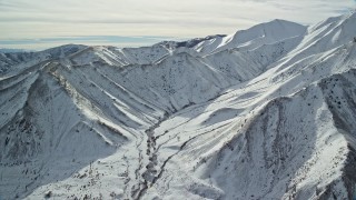 AX125_116E - 5.5K aerial stock footage of snowy mountain ridge in winter in the Oquirrh Mountains, Utah
