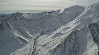 AX125_117 - 5.5K aerial stock footage of steep snowy slopes of a mountain ridge of the Oquirrh Mountains, Utah