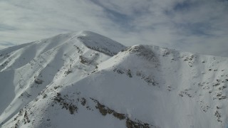 AX125_124 - 5.5K aerial stock footage of flying by one snowy Oquirrh Mountains peak toward Kessler Peak in winter, Utah
