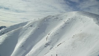 AX125_127 - 5.5K aerial stock footage approach small radio tower atop Kessler Peak in winter, Utah