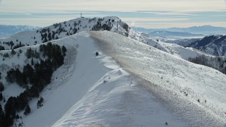 AX125_144 - 5.5K aerial stock footage fly over snowy mountain slope to approach Nelson Peak in winter, Utah