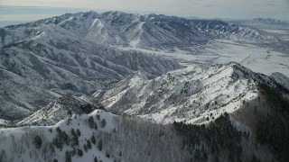 AX125_146 - 5.5K aerial stock footage fly over Oquirrh Mountain ridge with snow and trees in winter, Utah