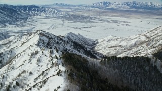 AX125_147 - 5.5K aerial stock footage fly over Oquirrh Mountains to approach wintery small town in Utah