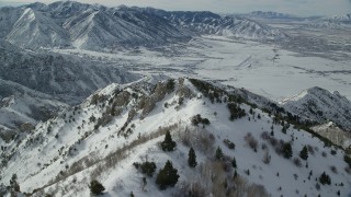 AX125_151 - 5.5K aerial stock footage of flying over wintery Oquirrh Mountains to approach Tooele, Utah