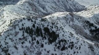 AX125_152 - 5.5K aerial stock footage fly over and orbit snowy ridges and slopes in wintertime, Oquirrh Mountains, Utah