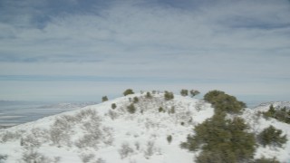 AX125_157 - 5.5K aerial stock footage of Great Salt Lake seen from snowy mountain slope in wintertime, Utah