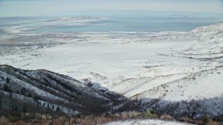 AX125_159 - 5.5K aerial stock footage of Great Salt Lake seen from wintery mountains in Utah