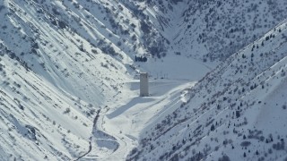 AX125_167 - 5.5K aerial stock footage of Baltimore Gulch with lone building in the Oquirrh Mountains with snow, Utah